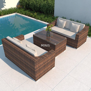 Sof&aacute; de mimbre marr&oacute;n para jard&iacute;n al aire libre con mesa de cristal